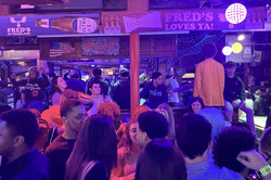 Hier sieht man eine Menschenmenge in einer Bar bei blauem Licht. 